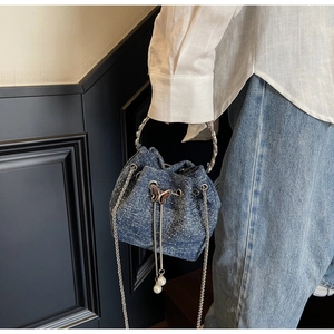 Detail of blue denim bucket bag with butterfly pearl pendant and sparkling rhinestones