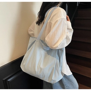 Close-up of light blue canvas tote bag featuring JUMAITU embossed detail and textured fabric
