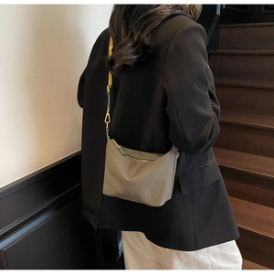 Close-up of neutral grey nylon crossbody bag with metal zipper and gold strap hooks