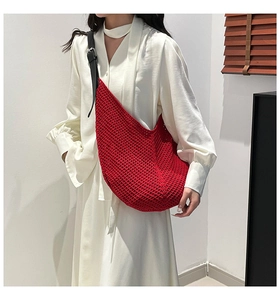 Detail of red crochet tote bag with thick knit texture and adjustable black strap