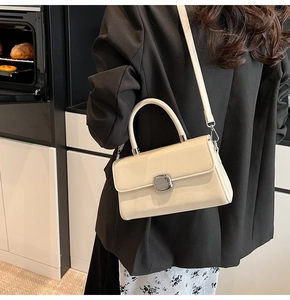 Chic cream leather handbag with silver square buckle and slim strap in a lifestyle scene