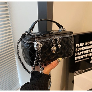 Detail of black quilted leather box bag with silver heart charm and chain strap