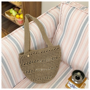 Detail of khaki hollow woven tote bag texture on a striped sofa for vacation style