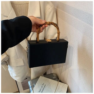 Detailed view of the black leather box bag featuring vintage bamboo handle and gold chain
