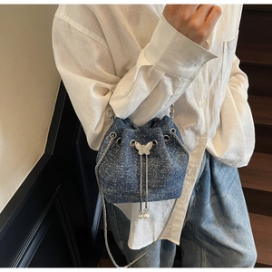 Detail of blue denim bucket bag featuring silver sparkles and metal butterfly charm