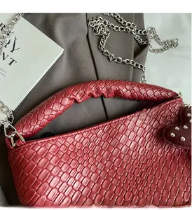 Close-up of dark red woven bucket bag with silver chain and heart rivet detail