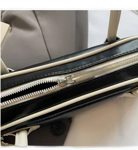 Detail of smooth silver metal zipper on a minimalist black and white leather bag