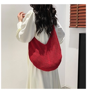 Detail of red hollow knit hobo shoulder bag with textured crochet pattern