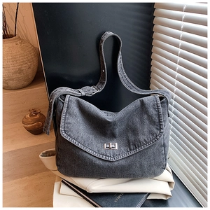 Dettaglio della borsa a tracolla in denim grigio scuro con chiusura girevole in metallo e tracolla