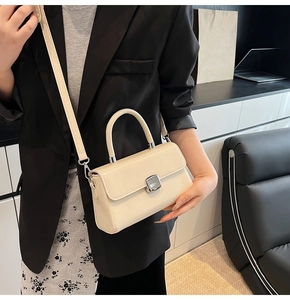 Chic beige leather handbag shown with silver metal clasp and crossbody strap detail
