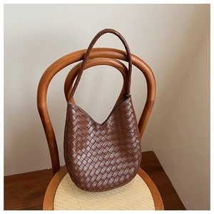 Gros plan d'un sac à bandoulière tressé marron suspendu à une chaise en bois vintage