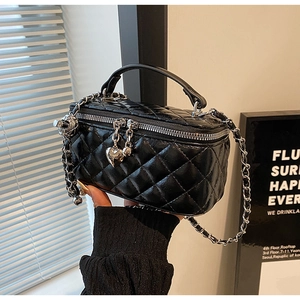 Detail of black quilted leather mini bag with silver chain strap and heart charm