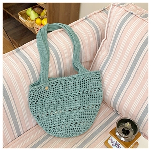 Detailed close-up of hollow-out hand-woven mint green tote bag on a cozy sofa