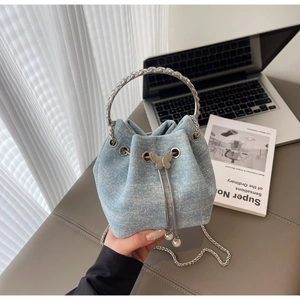 Close-up of light blue denim bucket bag with silver rhinestones and pearl butterfly detail