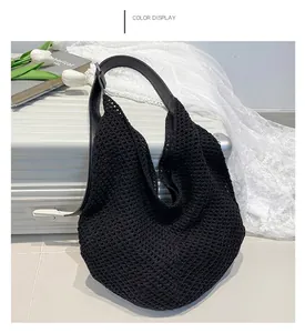 Close-up of black crochet knit tote bag with adjustable leather strap on a suitcase