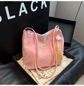 Detailed close-up of pink bucket bag with traditional embroidery and yellow tassel charm