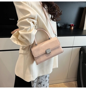 Detail of pink crossbody bag with silver buckle worn with a beige blazer and floral dress