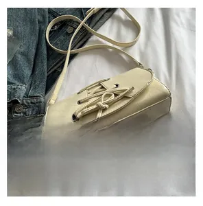 Detail of cream leather shoulder bag with cross-tie design next to a smartphone