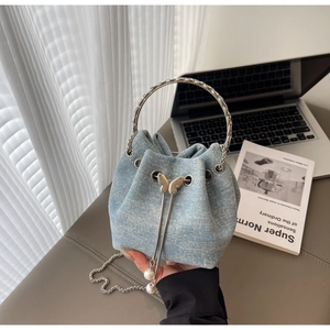 Detail of light blue denim bucket bag with rhinestones, silver ring handle and pearl charms