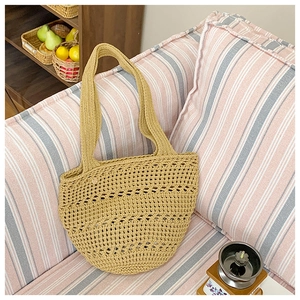 Detail of a yellow hand-woven crochet tote bag with hollow patterns on a cozy sofa