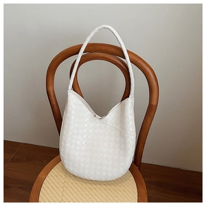 Détail du tissage blanc sur un sac à bandoulière en cuir suspendu à une chaise rétro