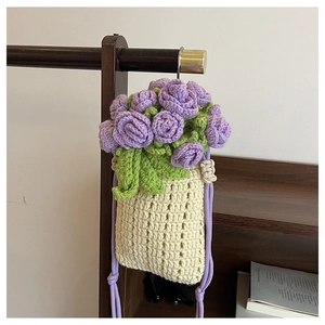 Detail of handmade crochet drawstring bucket bag featuring purple rose floral accents