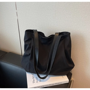 Close-up of black tote bag with JUMANTU logo detail and durable nylon shoulder straps