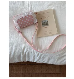 Detailed view of pink polka dot crossbody bag with white lace trim and adjustable strap