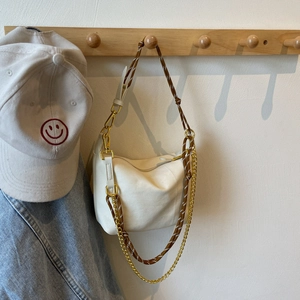 Detail of white nylon crescent bag with woven rope strap and gold chain accent