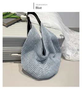 Close-up of blue knit beach bag with black shoulder strap next to silver suitcase