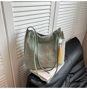 Detail of green silk tote bag with traditional Chinese embroidery and yellow tassel charm