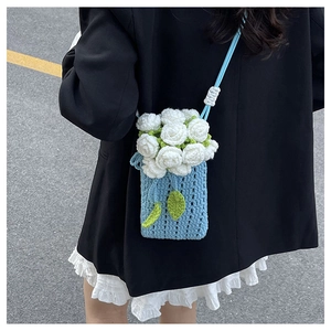 Détail du sac seau bleu clair crocheté à la main avec broderies de roses blanches
