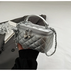 Close-up of silver quilted box bag featuring heart pendant zipper and metallic finish