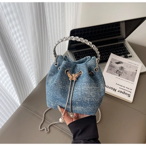 Detail of blue denim bucket bag with sparkling rhinestones and metal butterfly charm