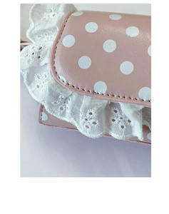 Detailed close-up of pink polka dot bag with white lace embroidery and fine leather texture