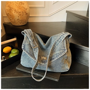 Dettaglio della borsa tote in denim blu con tracolla regolabile e chiusura a girello