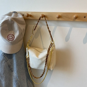 Detail of off-white nylon dumpling bag with woven rope strap and gold metal chain