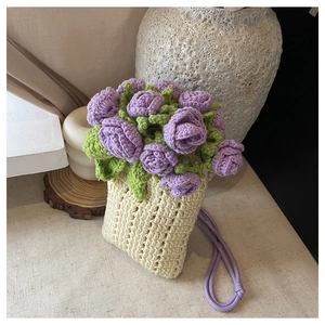 Detail of hand-crocheted beige bucket bag featuring delicate purple rose and leaf accents