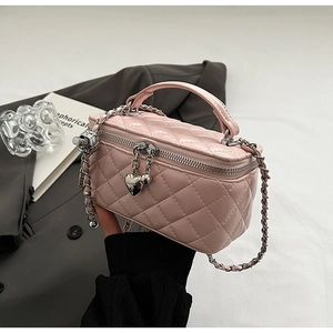 Detail view of pink quilted leather box bag with heart pendants and silver chain strap