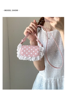 Detailed view of pink polka dot lace crossbody bag held by a girl in a white dress