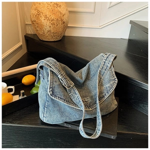 Dettaglio ravvicinato della borsa tote in denim blu con chiusura a scatto e tracolla larga