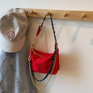Detail of red nylon dumpling bag featuring woven rope strap and gold metal chain