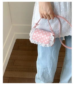 Detail of pink polka dot mini bag with white lace edges and adjustable shoulder strap