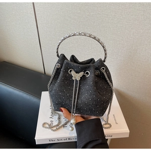 Detail of denim bucket bag featuring crystal handle, silver butterfly and pearl chain