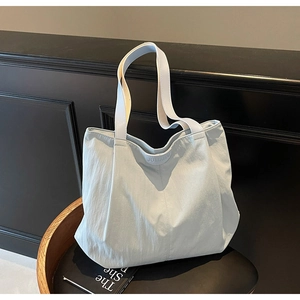 Detail of light blue nylon tote bag with leather logo patch on a wooden background