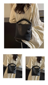 Detail shot of black woven bucket bag with crocodile pattern and silver metal chain strap