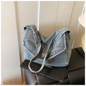 Dettaglio del tessuto denim blu lavato e della fibbia sulla tracolla regolabile della borsa hobo