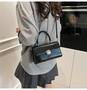 Detailed side view of black vintage crossbody bag with silver buckle on a person