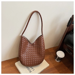 Détail d'un grand sac cabas en cuir tressé marron caramel avec une texture élégante