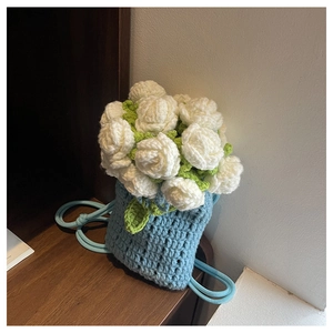 Detailed close-up of light blue hand-knitted bucket bag with crochet roses and leaves